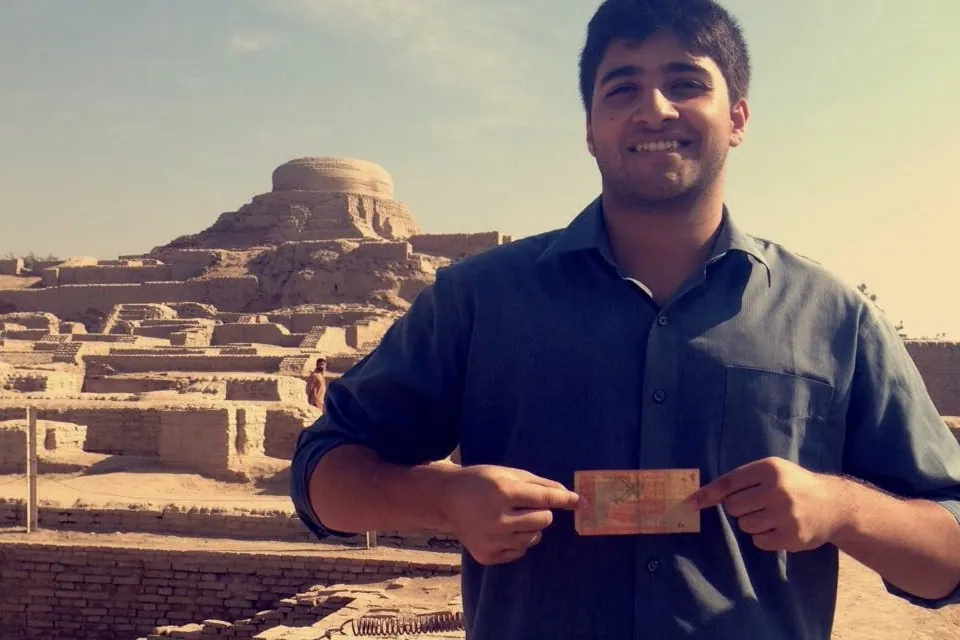 Emaad holding the 20 rupee note in front of the ruins of Mohenjodaro in 2015